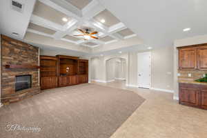Unfurnished living room with arched walkways, a fireplace, coffered ceiling, recessed lighting, and beamed ceiling
