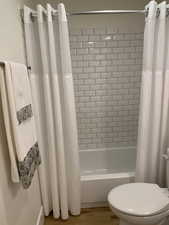 Bathroom with shower / bath combo with shower curtain and wood finished floors