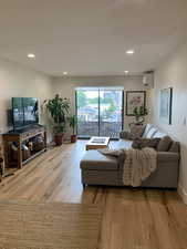 Living room with wood-type flooring, recessed lighting, and a wall unit AC