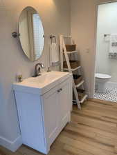 Half bath with vanity, light wood finished floors, and a textured wall