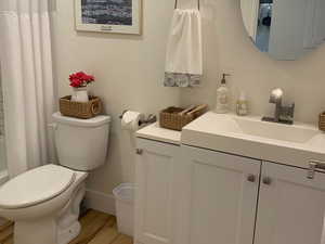 Full bathroom featuring vanity, light wood-style floors, shower / bath combination with curtain, and a textured wall