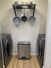 Washroom featuring washer / dryer, light wood-style floors, and a textured wall