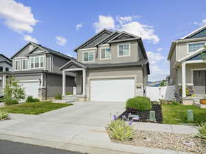 Craftsman inspired home with a garage, stucco siding, concrete driveway, board and batten siding, and stone siding