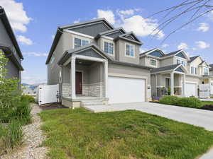 Craftsman-style home with stone siding, stucco siding, driveway, an attached garage, and a front yard