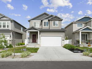 Craftsman inspired home featuring concrete driveway, stucco siding, an attached garage, board and batten siding, and a gate