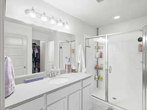 Full bathroom with a spacious closet, a stall shower, vanity, recessed lighting, and light marble finish flooring