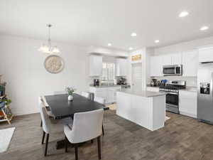 Kitchen with white cabinets, stainless steel appliances, a kitchen island, a chandelier, and recessed lighting