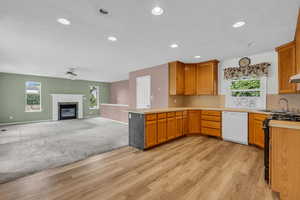 Kitchen with light countertops, a premium fireplace, black range with gas stovetop, dishwasher, and recessed lighting