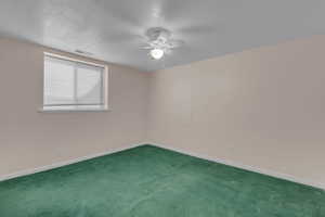 Spare room featuring carpet, a ceiling fan, and a textured ceiling