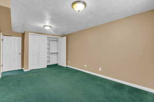 Unfurnished bedroom with a textured ceiling, carpet floors, and a closet
