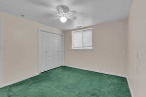 Unfurnished bedroom with carpet, a ceiling fan, a closet, and a textured ceiling