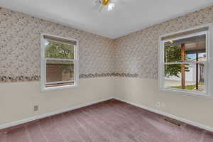 Carpeted empty room featuring wallpapered walls