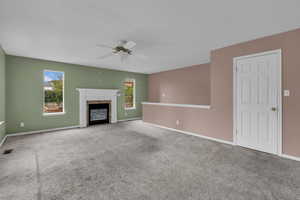Unfurnished living room with a high end fireplace, a ceiling fan, and carpet floors