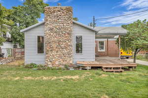 Rear view of property featuring a deck, a chimney, and brick siding