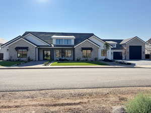 Modern inspired farmhouse featuring a front lawn, a standing seam roof, driveway, and brick siding