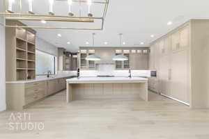Kitchen featuring a large island, light brown cabinetry, light stone countertops, pendant lighting, and a breakfast bar