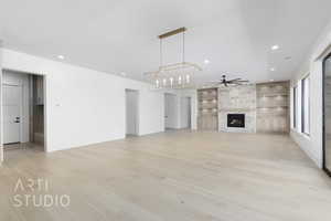 Unfurnished living room featuring ceiling fan, light wood finished floors, recessed lighting, a fireplace, and built in features