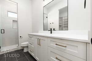 Full bathroom with vanity, a shower stall, and dark tile patterned flooring