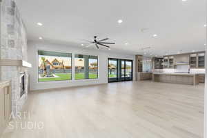 Unfurnished living room with a stone fireplace, light wood-style floors, recessed lighting, and ceiling fan