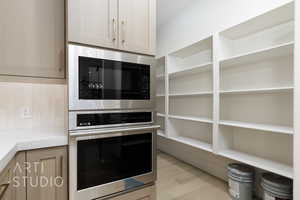 Kitchen featuring appliances with stainless steel finishes, light wood finished floors, light brown cabinets, and tasteful backsplash