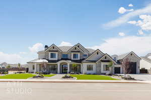 Craftsman-style house with a front lawn, driveway, a standing seam roof, a chimney, and stone siding