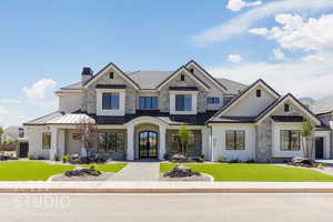 View of front facade featuring a standing seam roof, a front yard, a metal roof, and stone siding