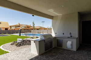 Fenced backyard with exterior kitchen, a patio, and a residential view