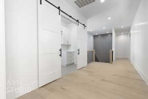 Hall featuring a barn door, recessed lighting, and light wood-type flooring