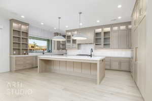 Kitchen featuring a large island, backsplash, a kitchen bar, light wood finished floors, and light stone countertops