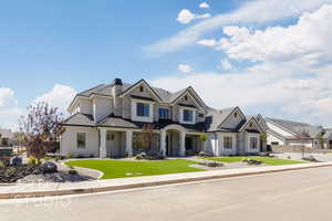 View of front of house featuring a front yard, a standing seam roof, a metal roof, stone siding, and a porch