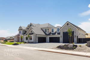 View of front facade featuring decorative driveway, stone siding, and an attached garage