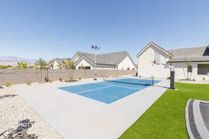 View of tennis court featuring basketball hoop and a residential view