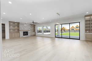 Unfurnished living room with built in features, light wood-type flooring, a stone fireplace, recessed lighting, and ceiling fan