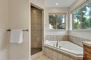 Full bath with a whirlpool tub, vanity, tile patterned flooring, and a tile shower