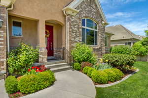 Property entrance featuring stucco siding, brick siding, covered porch, and stone siding