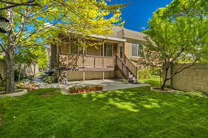 Rear view of property with stucco siding, a patio, a lawn, stairs, and roof with shingles