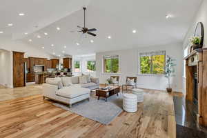 Living area with a premium fireplace, light wood-style flooring, high vaulted ceiling, recessed lighting, and arched walkways