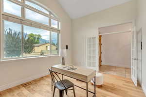 Office with a mountain view, light wood-style flooring, and lofted ceiling