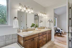 Bathroom featuring double vanity, light tile patterned floors, and a bath