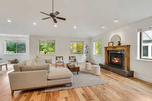 Living room featuring plenty of natural light, a tiled fireplace, light wood-style flooring, and recessed lighting