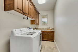 Washroom featuring light tile patterned floors, cabinet space, and washer and dryer