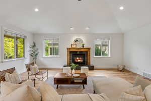 Living area featuring recessed lighting, wood finished floors, a premium fireplace, and vaulted ceiling