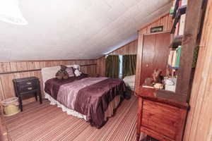 Bedroom with wood walls and vaulted ceiling