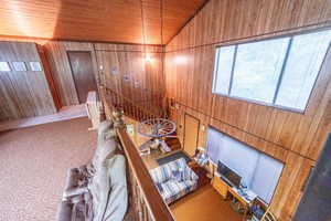 Stairs with wood walls, carpet, wood ceiling, and high vaulted ceiling