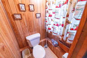 Full bath featuring wooden walls and toilet
