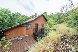 View of home's exterior with a view of trees and a deck