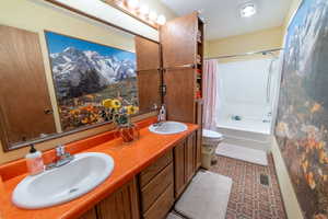 Full bath featuring shower / bath combination with curtain, double vanity, and tile patterned flooring
