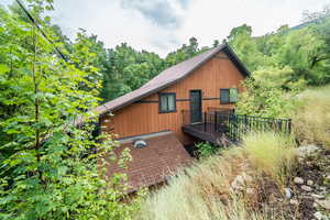 View of side of property featuring a metal roof and a view of trees