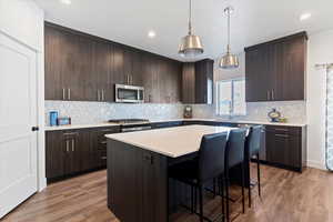 Kitchen featuring dark brown cabinets, a kitchen bar, backsplash, dark wood-type flooring, and modern cabinets