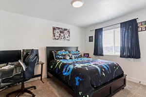 Carpeted bedroom with an office area and a textured ceiling